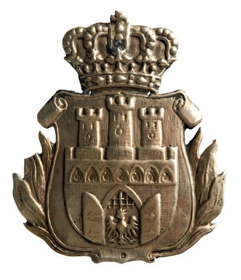 (729) Blaszany kartusz herbowy z płomienistymi liśćmi
laurowymi z herbem Krakowa, o wymiarach 8,2 x 7 cm,
do przypinania. Prawdopodobnie odznaka którejś ze służb
miejskich w drugiej połowie XIX w.
(MK, nr inw. MHK 454/III)
